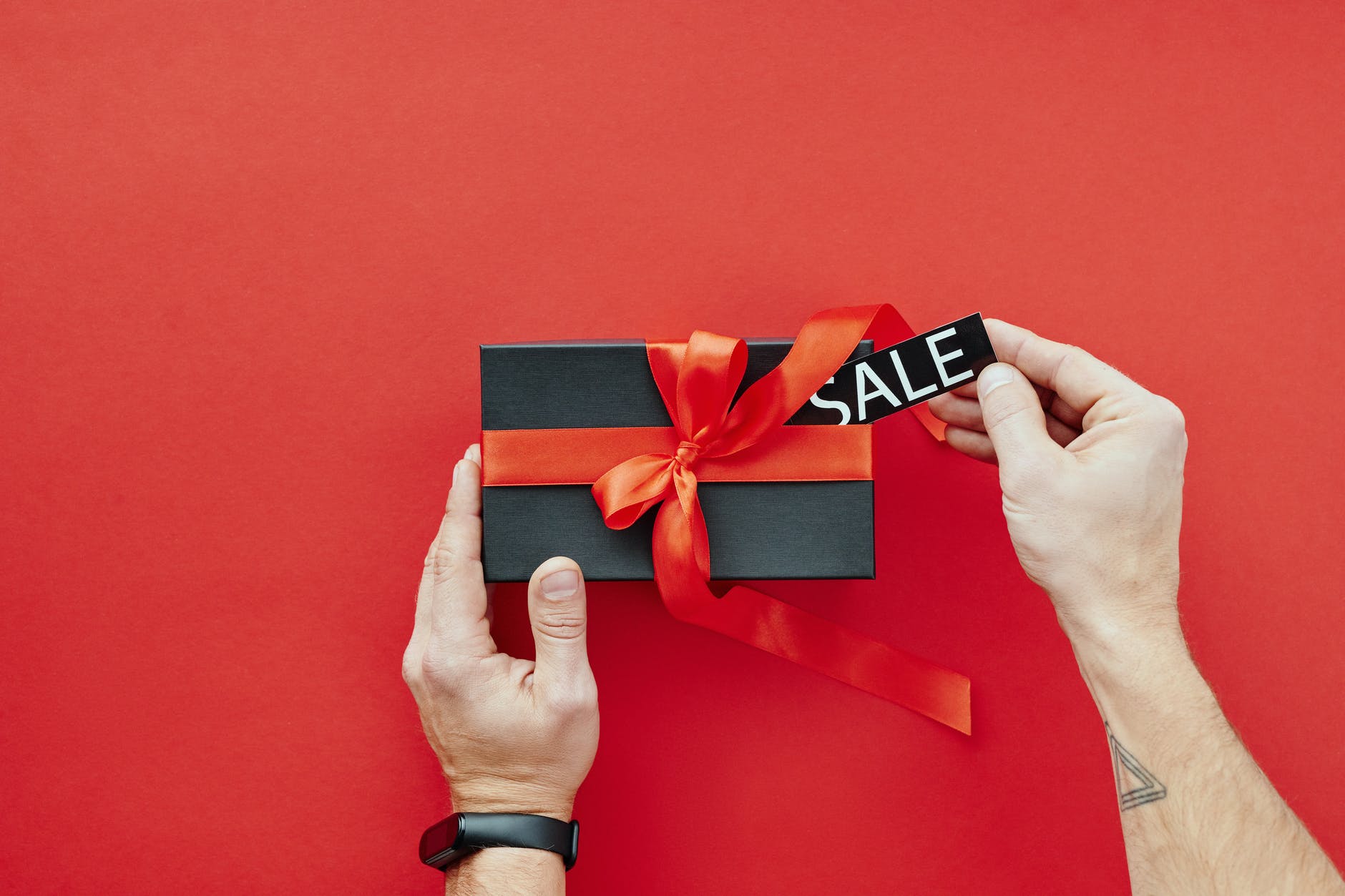 person holding red and black box with red ribbon