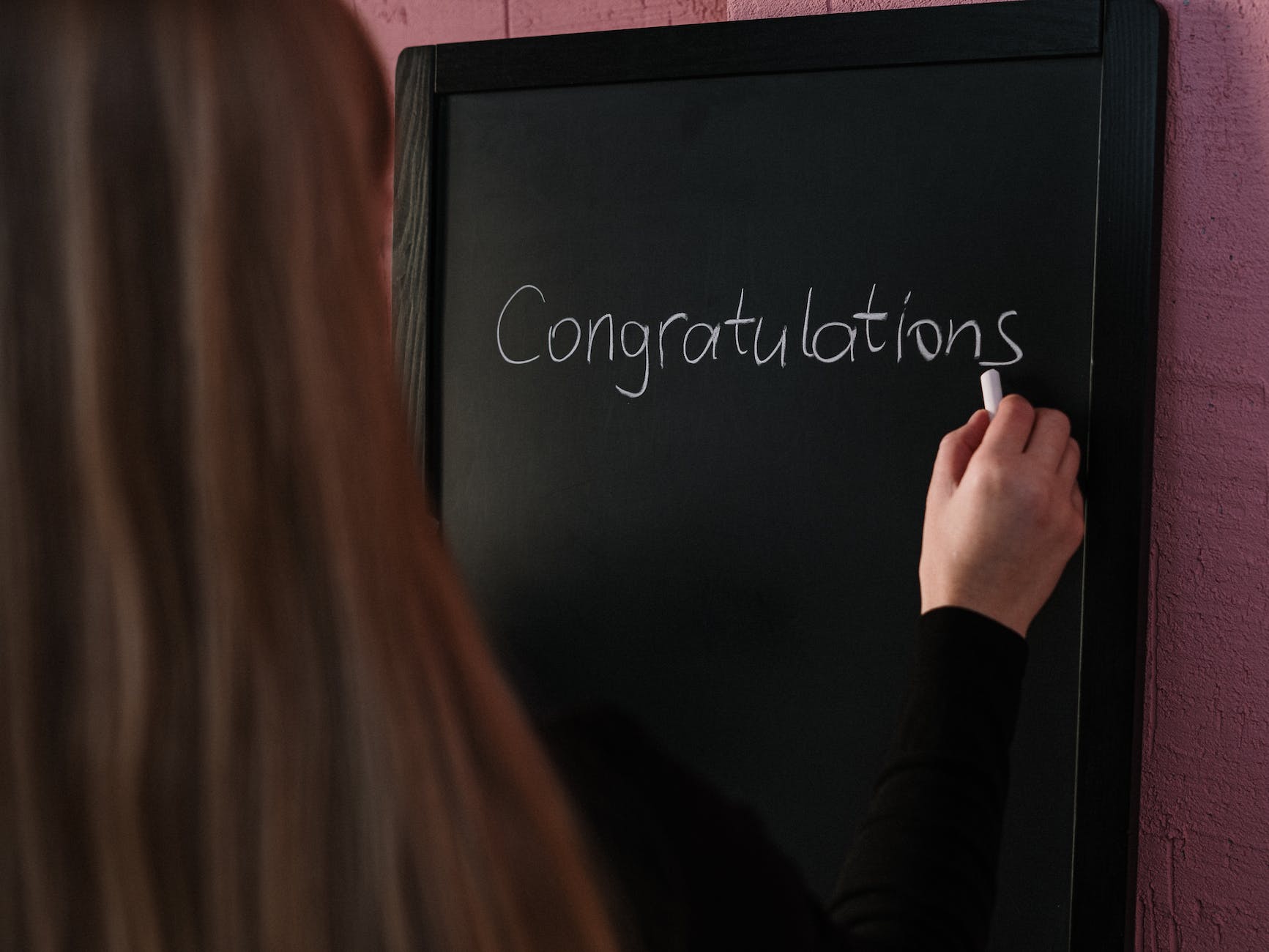 woman in black long sleeve shirt writing on the chalkboard